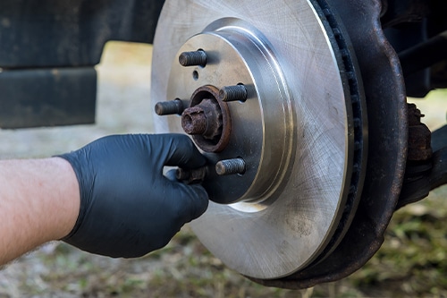 Car mechanic repair service doing brake repair by changing car disc brake pads from old brakes to new brakes.