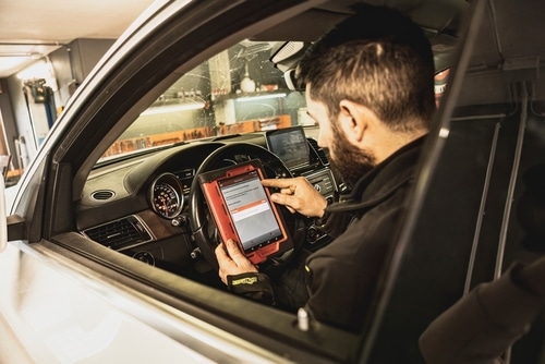 Barney Brothers' Guide to Vehicle Diagnostics for On & Off-Road Enthusiasts in Grand Junction, CO. Image of male technician sitting inside a vehicle in the shop using a scanning tool to perform professional diagnostics.