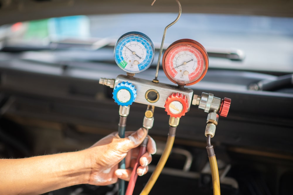 Auto Air Conditioning Repair near me in Grand Junction, CO, by Barney Brothers Off Road and Repair. Image of a technician using a refrigerant gauge to measure the AC system levels, showcasing the professional and detailed auto air conditioning services offered by Barney Brothers Off Road and Repair in Grand Junction, CO.