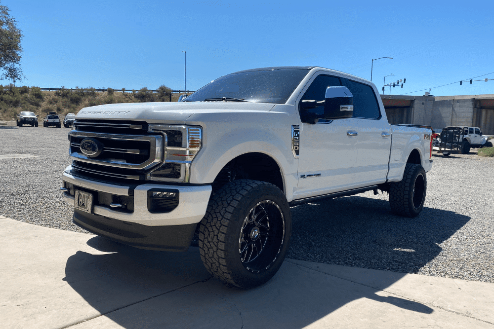 A/C repair in Grand Junction, CO by Barney Brothers Off Road & Repair. White Ford Super Duty under summer sun, showing the need for heat-ready cooling system checks.