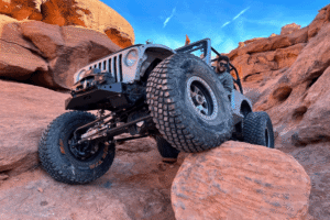 Tire size and gear ratio, off-road and repair by Barney Brothers Off Road & Repair in Grand Junction, CO. Image of a lifted Jeep rock crawling over large boulders with oversized off-road tires and upgraded axle components. Highlighting traction, drivetrain performance, and extreme terrain safety.